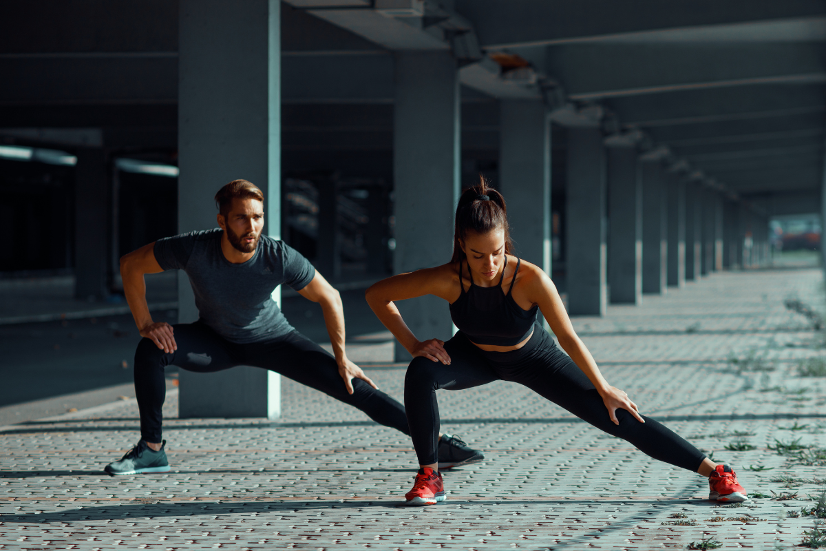 Two people stretching in a side lunge position 