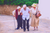 Three senior citizens walking arm in arm. Woman on the left is using a cane, a man is in the center and a woman carrying a brown purse is on the right.
